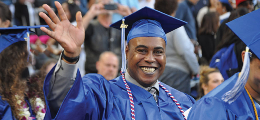  South Seattle College graduate waiving at Commencement 