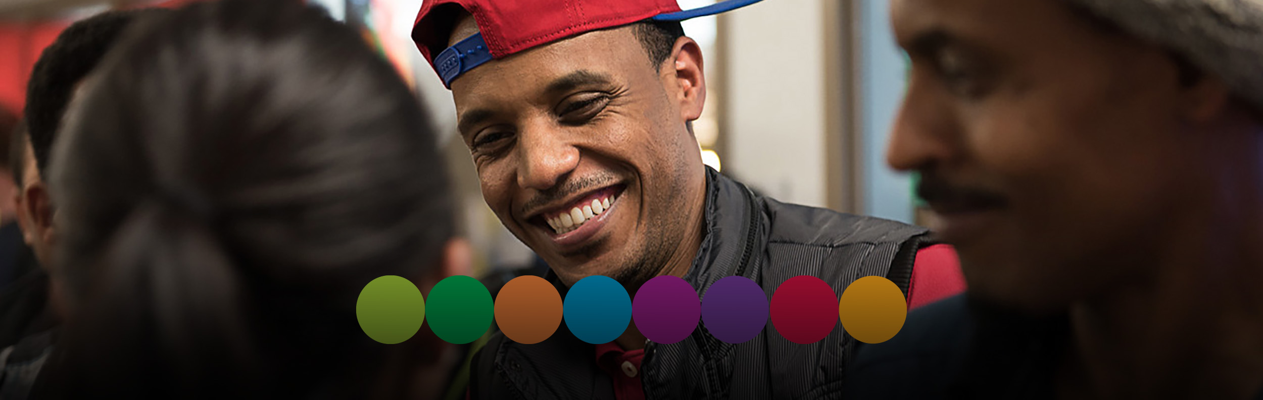 Photo of student smiling wearing a red baseball cap backwards 