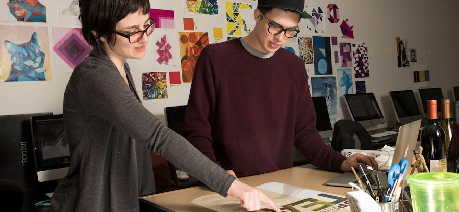  student and faculty member reviewing graphic design work 