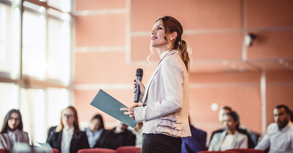 woman with microphone presenting to group