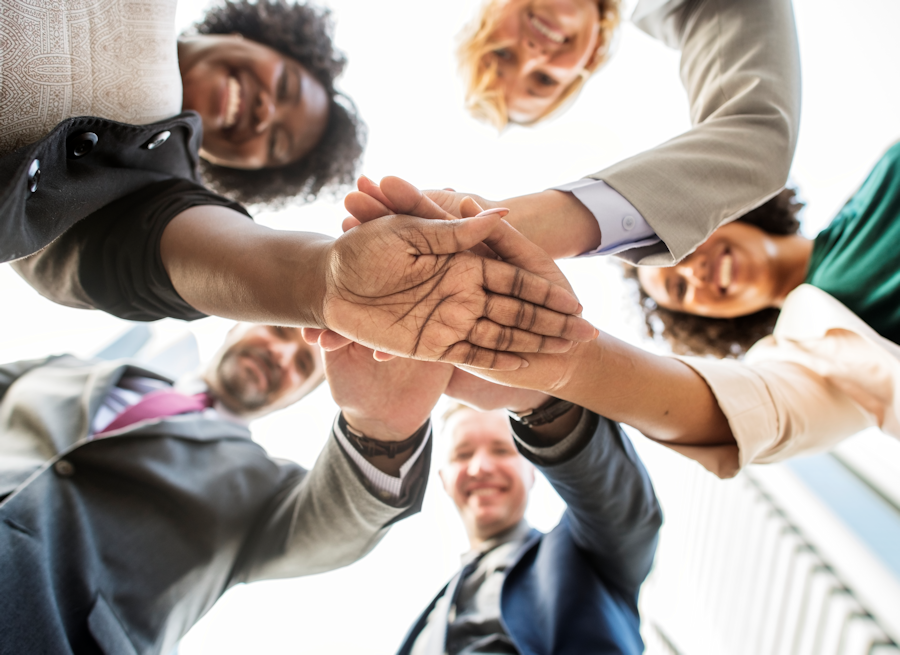  a diverse team of people putting their hands on top of each others' hands 