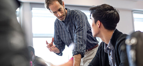  faculty member with student in a classroom 