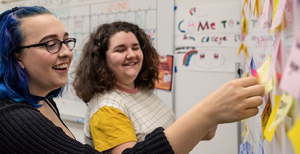  two students in a class at an info board 