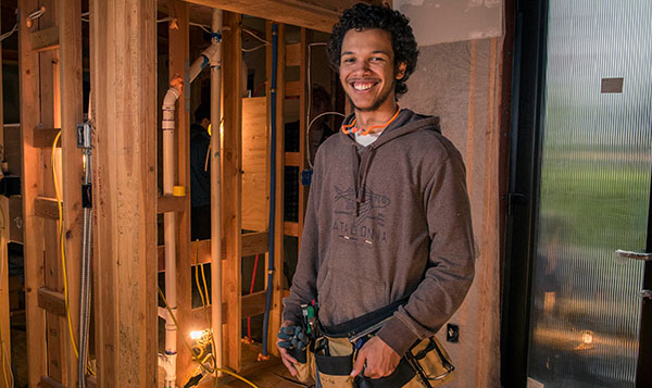  smiling student at the Wood Technology Center in a construction setting 
