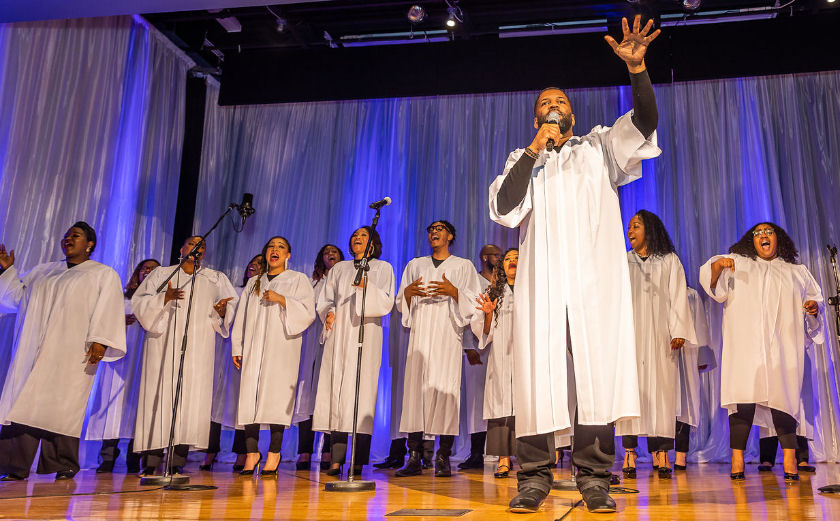  members of a gospel choir dressed in robes and singing 