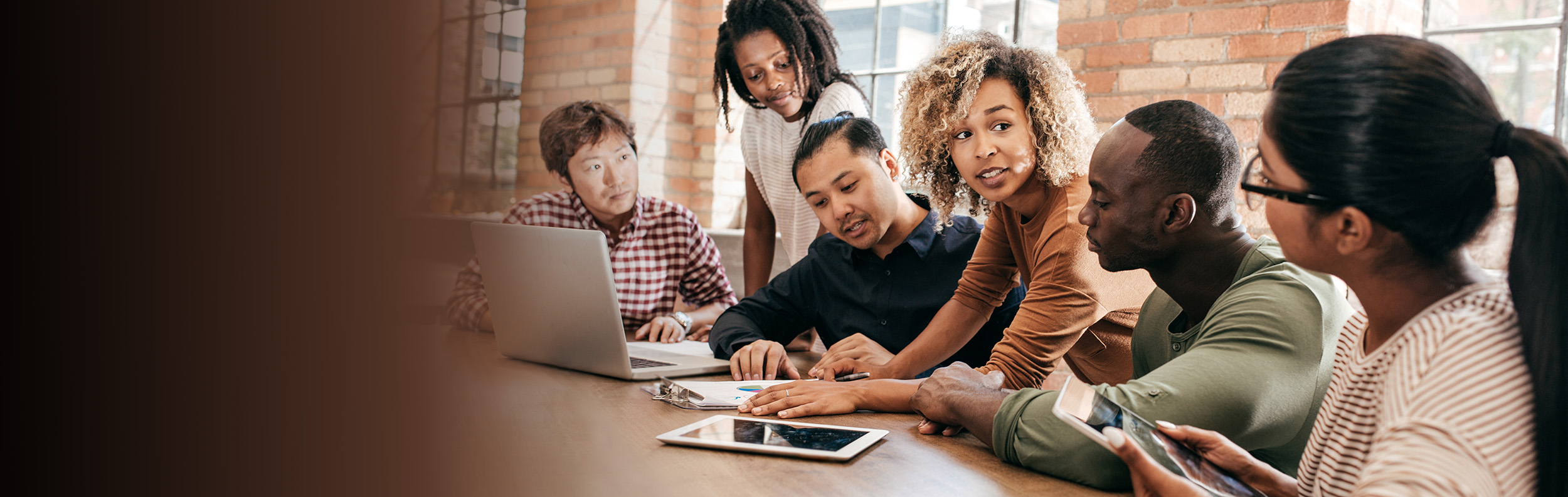  a diverse team of people talking at a table with computers 