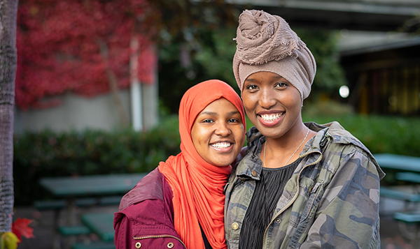  two smiling students wearing traditional head coverings 