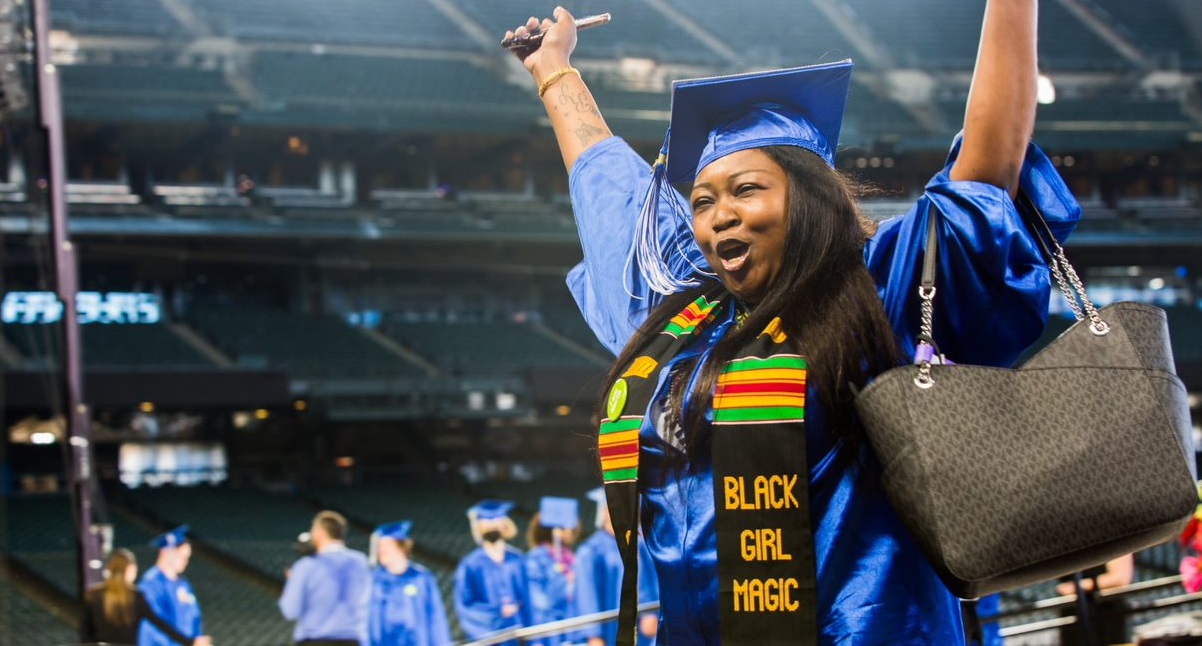  A student joyfully raising her arms after crossing the stage at commencement 