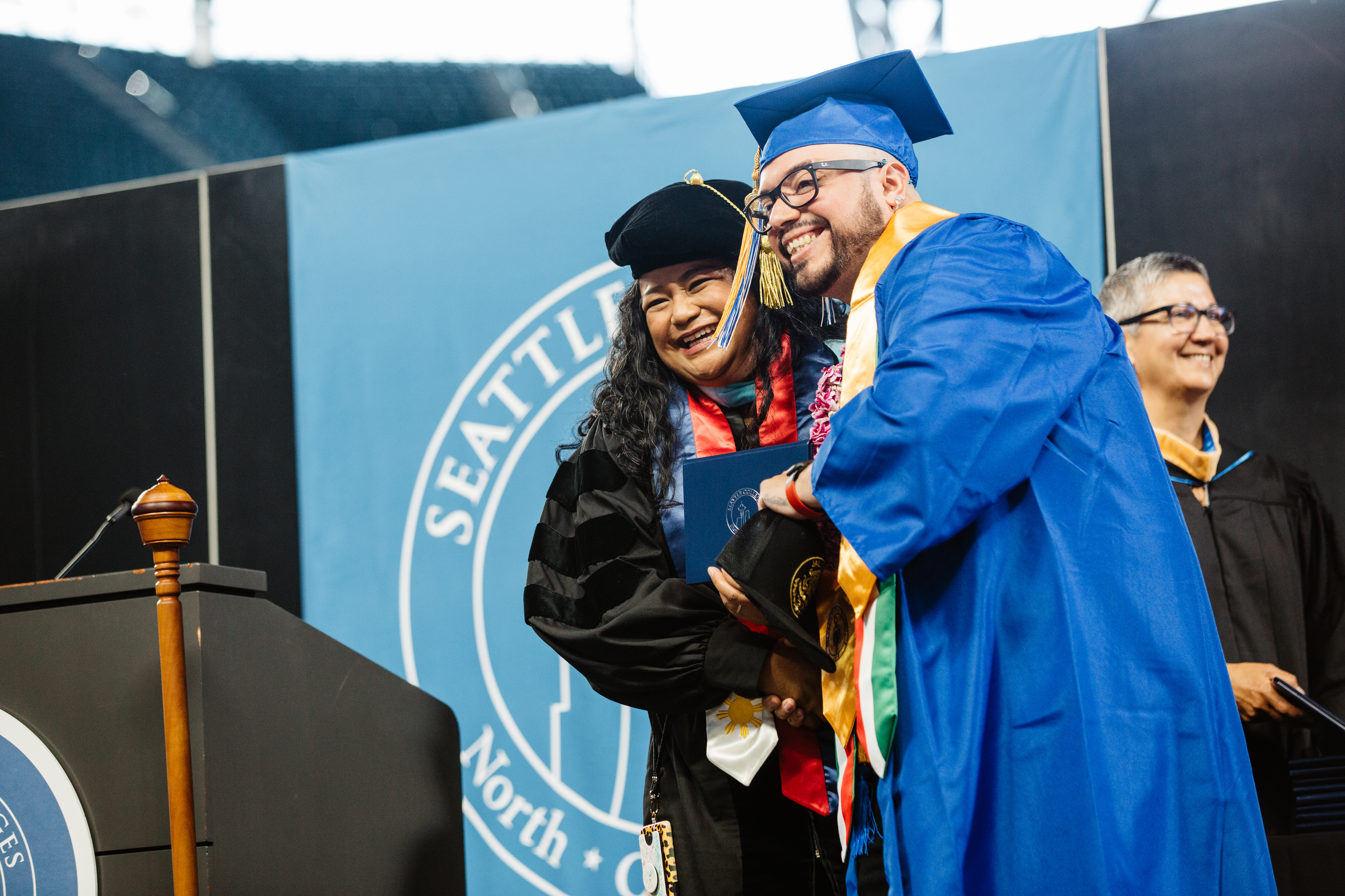 crossing the stage, a student gets a hug from the chancellor
