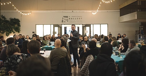 A community dinner at Seattle Central with people seated at tables in the atrium area 