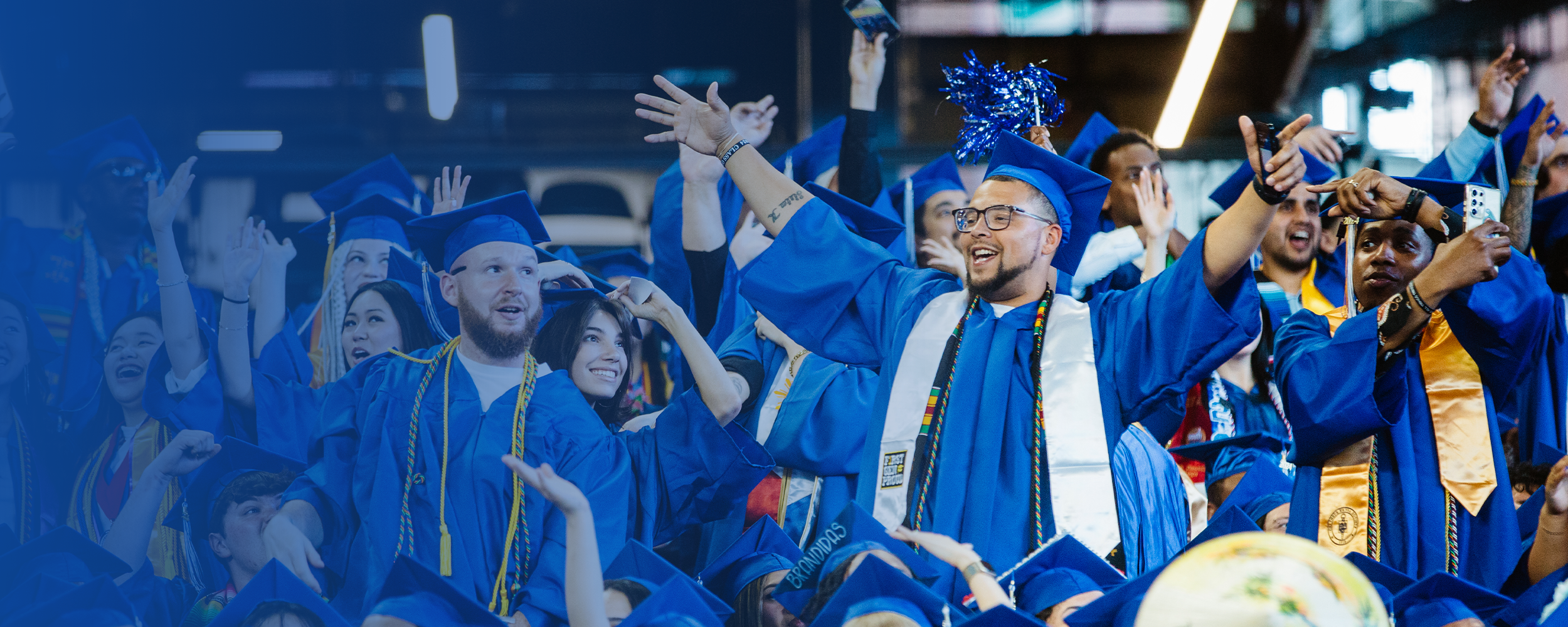 several smiling students in caps and gowns at commencement