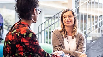 A staff member interacting with a student in a lounge area on campus