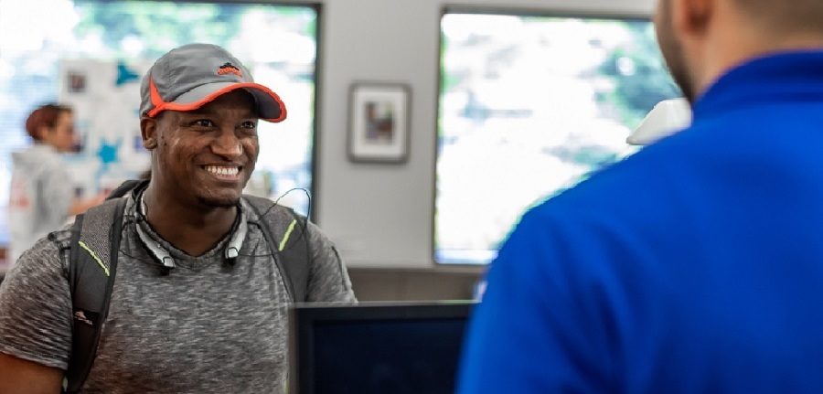 A smiling student interacting with a staff member in the Financial Aid office