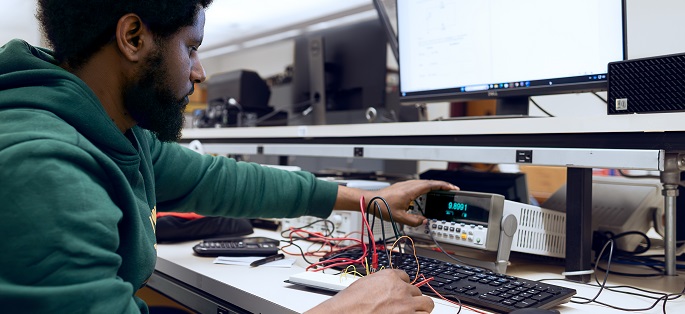 a student working with electronics equipment at a computer