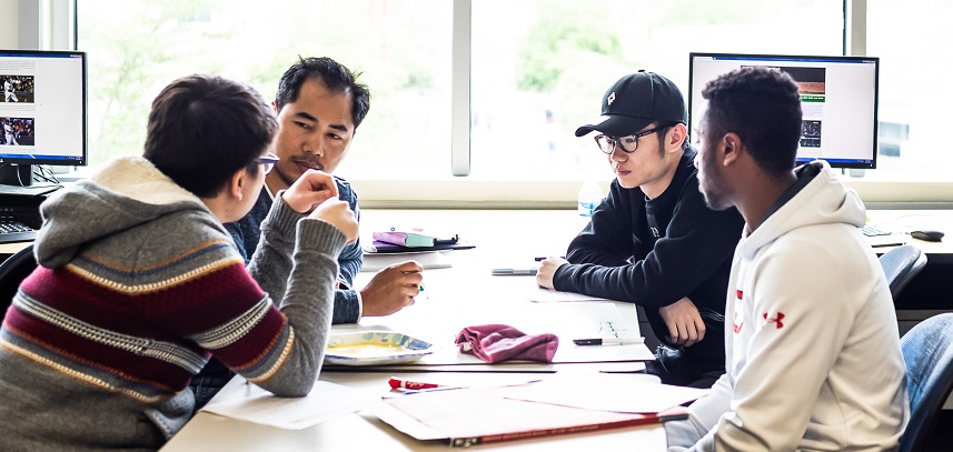 a group of four students of diverse backgrounds talking together at a table