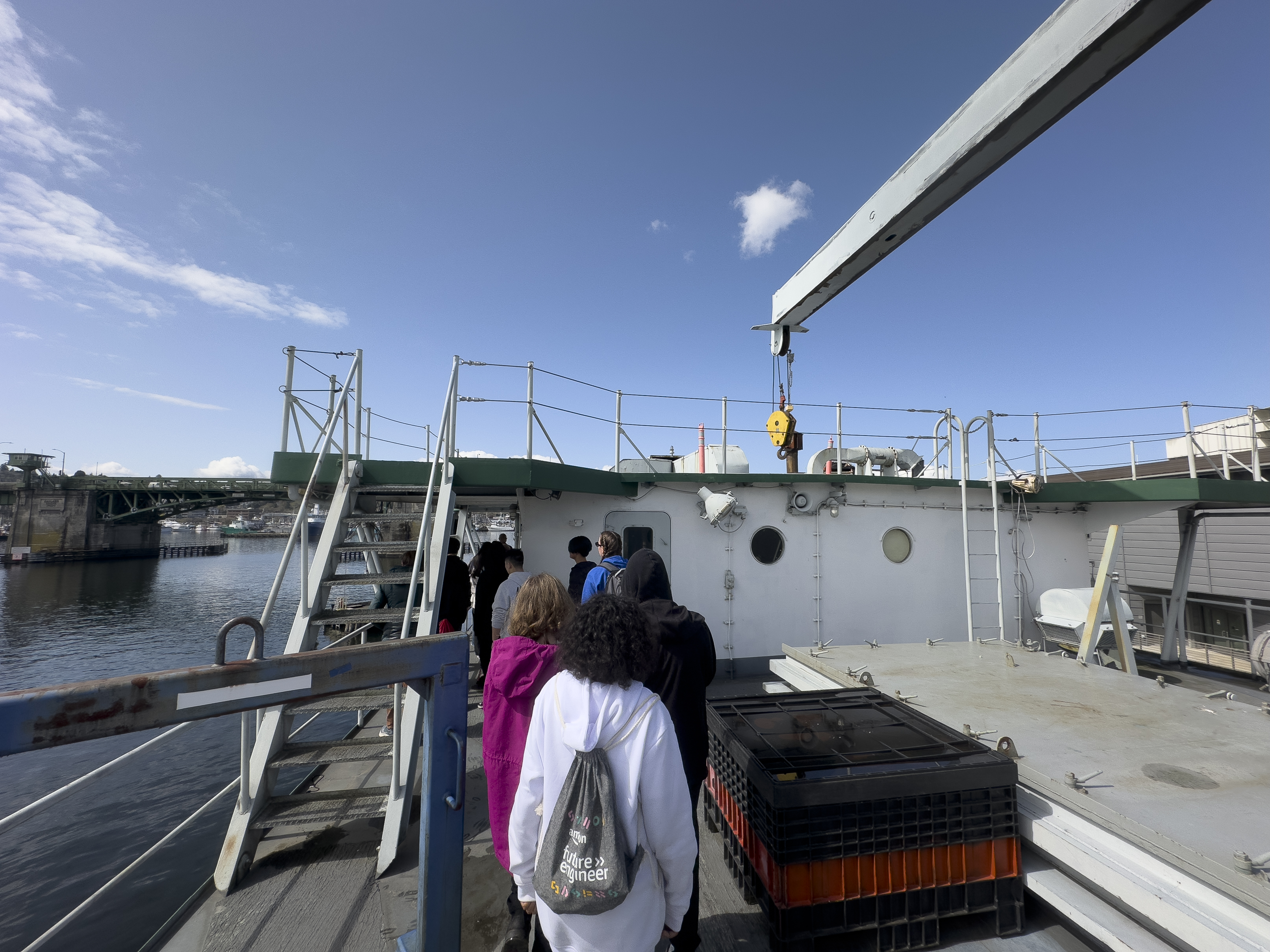 Students touring the upper deck of the Vulcan. Above them, a crane that can reach through the vessel's decks to move equipment and machinery.