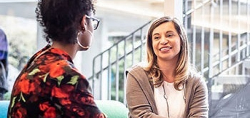 A staff member interacting with a student in a lounge area on campus