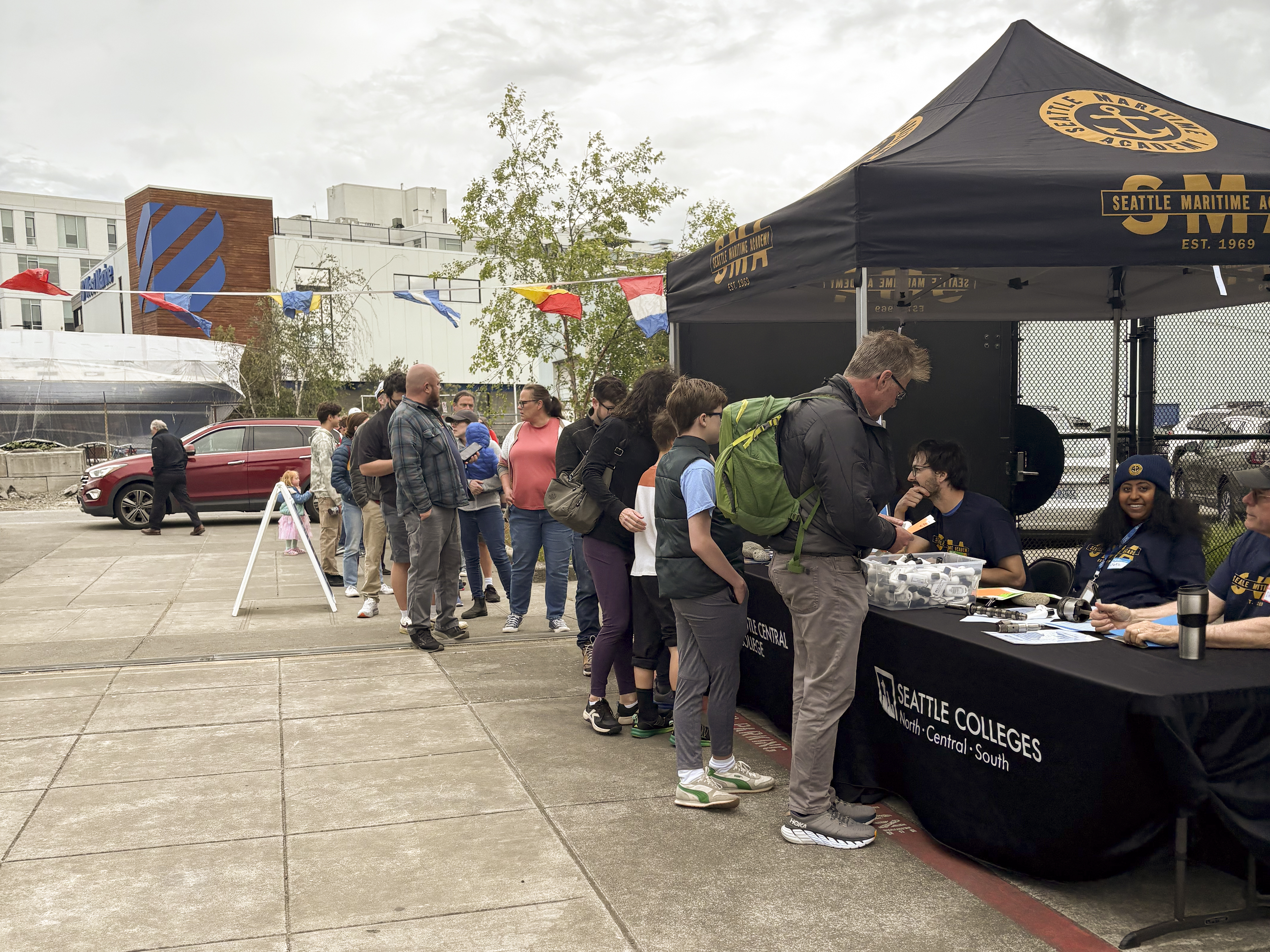 Attendees at Seattle Maritime Academy Community Day held on May 31st line up at several tables.