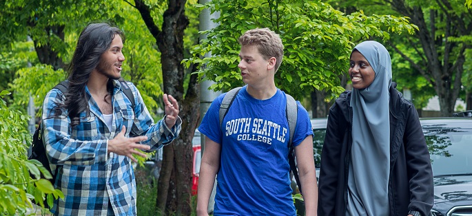 Three smiling students interacting outdoors on the South Seattle College campus