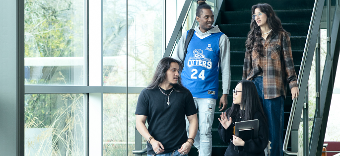Four students engaging in conversation as they walk down a staircase at South Seattle College.
