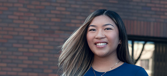 Isabella smiling standing in front of Seattle Central's brick exterior