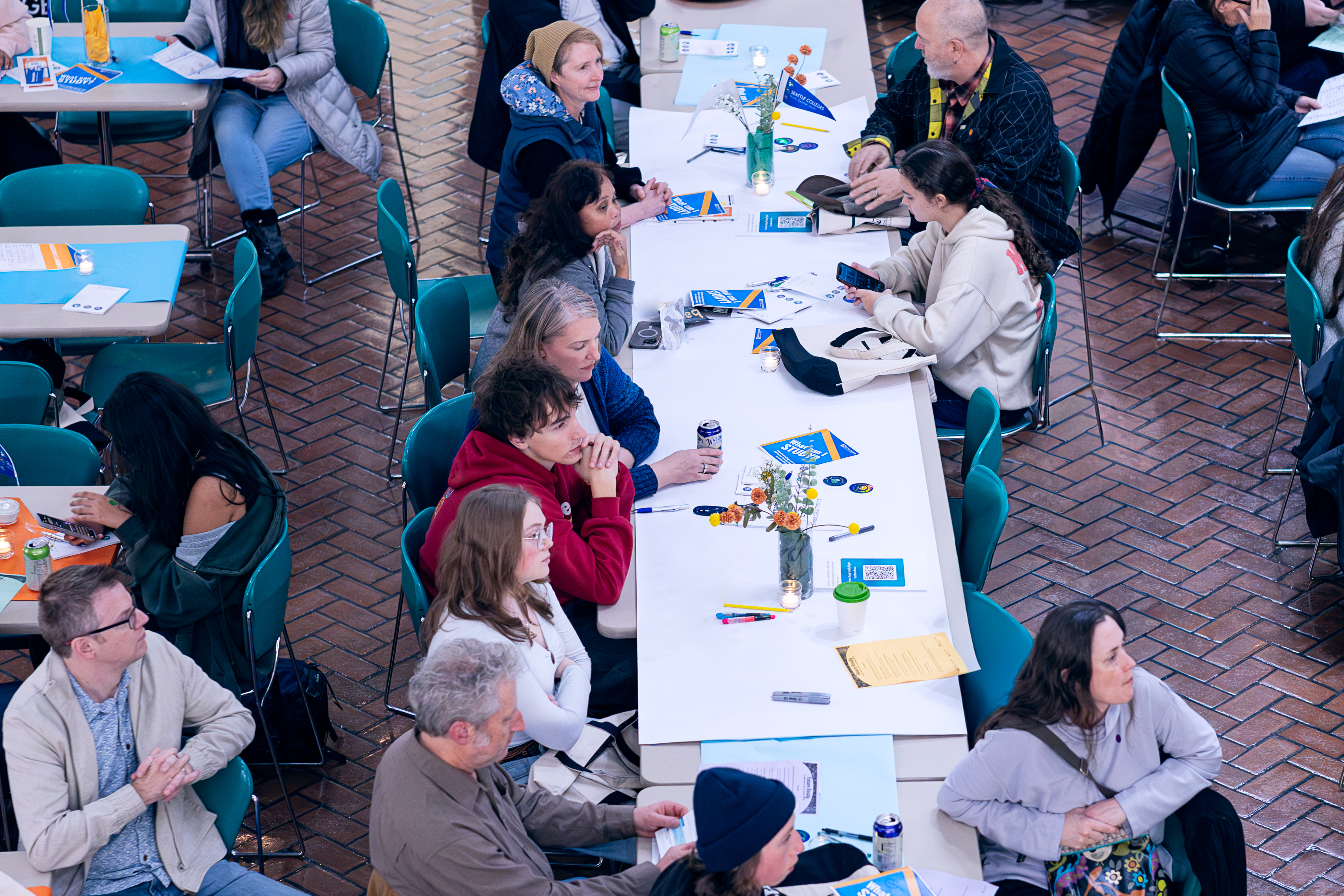 Attendees and family members sit at table listening to speaker