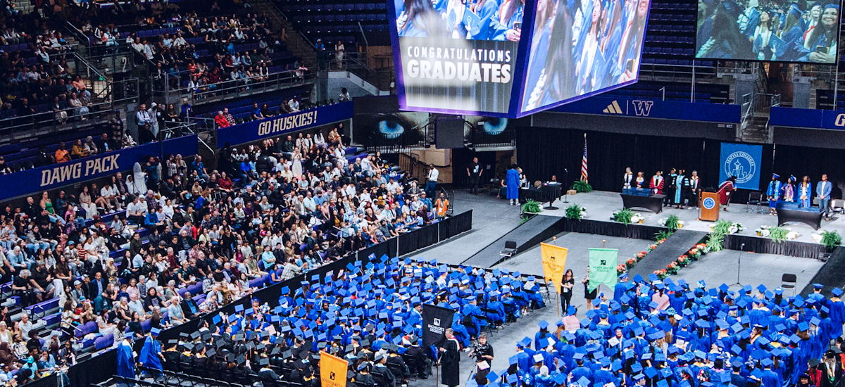 a view of the area with graduates in cap and gown seated en masse on the main court 