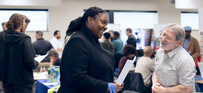 two people smiling and interacting in a group setting