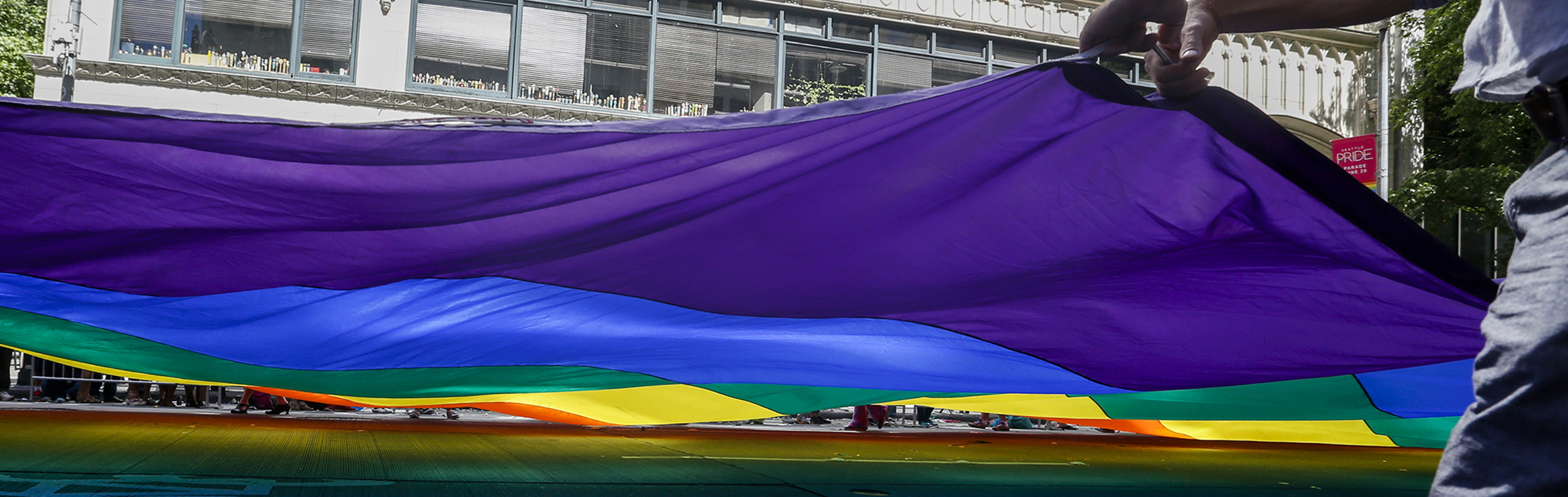 people holding the six-color pride flag in the Seattle Pride parade