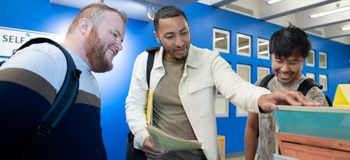three young men interacting and smiling