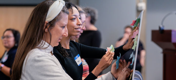 two women of diverse backgrounds engaging in a planning exercise at easels