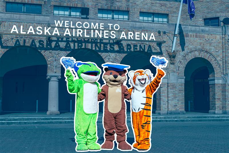 Photo of the three Seattle Colleges mascots -- Star the Treefrog from North, Olivia the Otter from South, and Theo the Tiger from Central -- standing in front of the entrance to Alaska Airlines Arena.