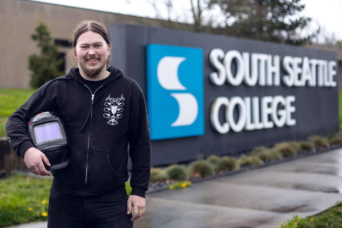 Floyd Saygor smiling in front of South Seattle College's big sign