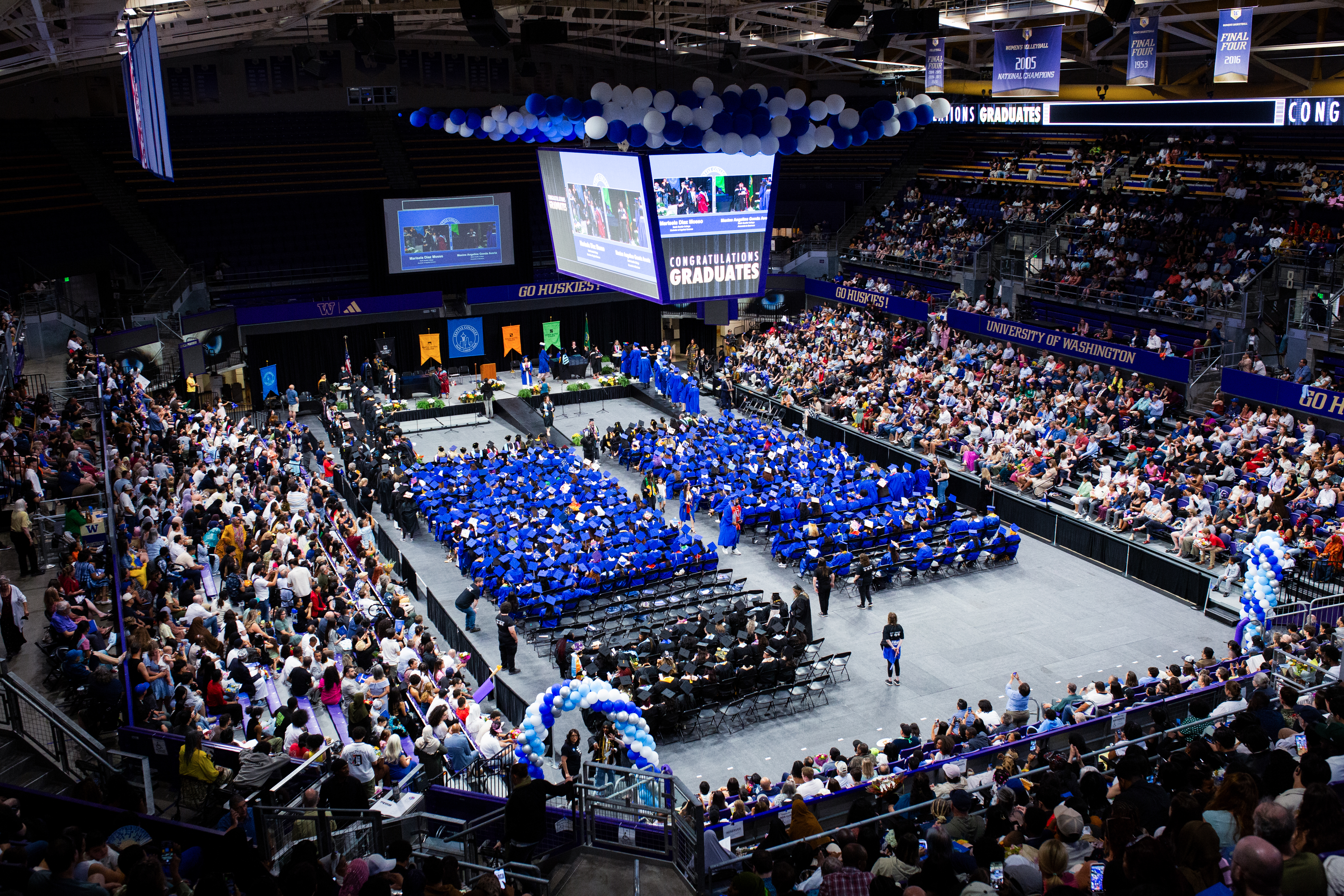 a view of the commencement floor at Alaska Airlines Arena with graduates seated and hundreds of friends and family in the stands