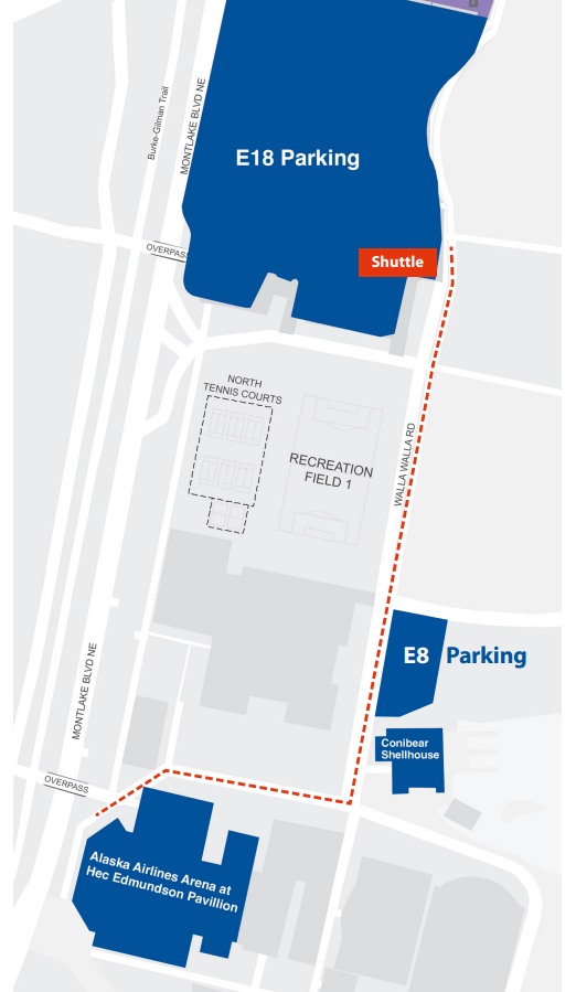 Parking Lot E-18 in respect to Alaska Airlines Arena. The parking lot is about three blocks north of the arena along Montlake Boulevard NE. A golf cart shuttle stop is located in the southeast corner of the lot near Wahkiakum Road. The golf cart shuttle will run from that stop to a stop near the northwest entrance of Alaska Airlines Arena. A suggested walking path from Lot E-18 goes from the south end of the lot south on the sidewalk that follows Montlake Bouldevard until it meets the northwest entrance of the arena.