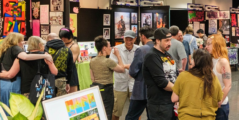 Students meeting and mingling with the public at the Portshowlio event among booths with each students work