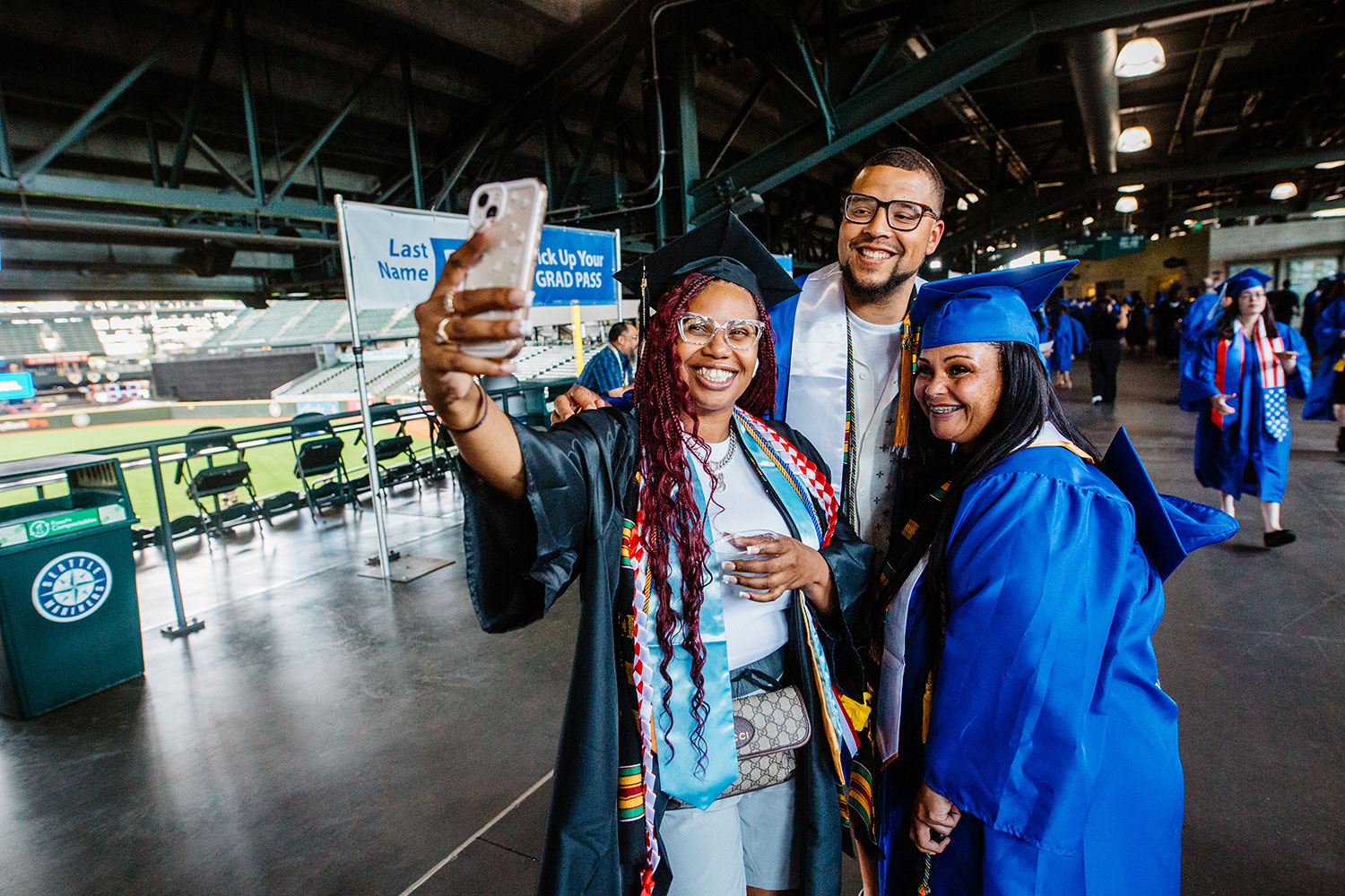 Students smiling at Seattle Colleges Commencement wearing caps and gowns