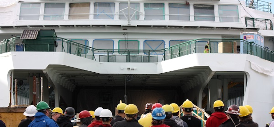 A marine ferry with several men wearing hardhats standing near it at Harbor Island Training Center