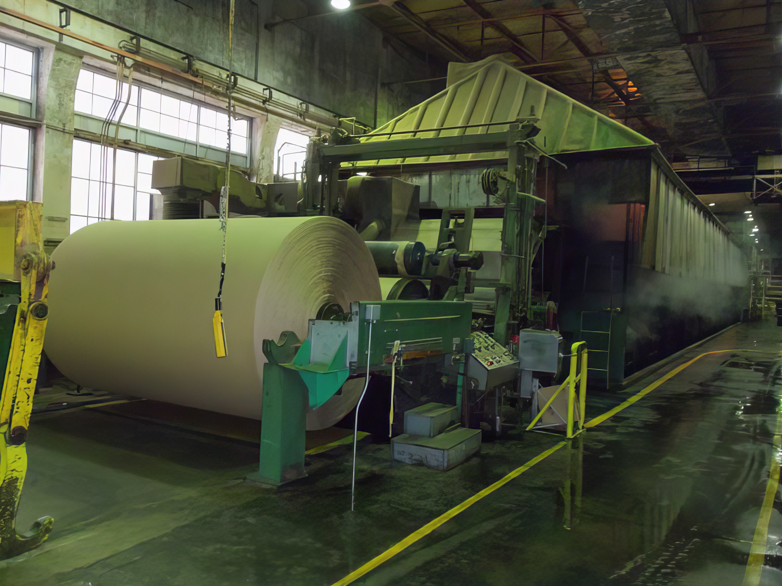 A view of one of the paper mill's manufacturing lines. The photo describes the large scale of the products and the machinery needed to process them.